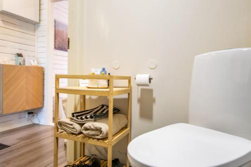 a room with a toilet and a shelf with towels at Coastal Wooden Apartment Rauma in Rauma