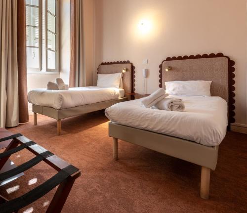 a bedroom with two beds and a chair in it at Hotel Louvia in Menton