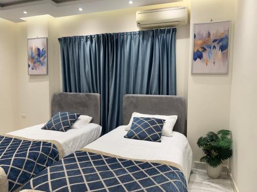 two beds in a room with blue curtains at Colour holiday Zayed in Sheikh Zayed