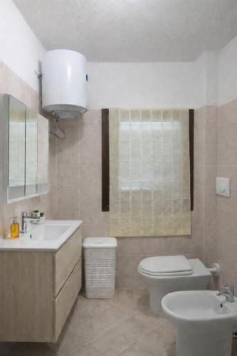 a bathroom with a white toilet and a sink at Il Mirto apartment con piscina in Olbia