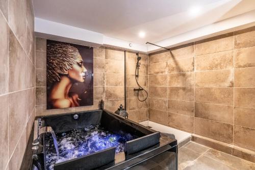 a bathroom with a tub with a painting on the wall at La Cachette - Suite romantique & balnéo privative in Hermeray