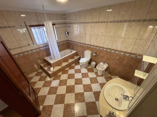a bathroom with a toilet and a tub and a sink at Casa dos Neto Carriço in Anadia
