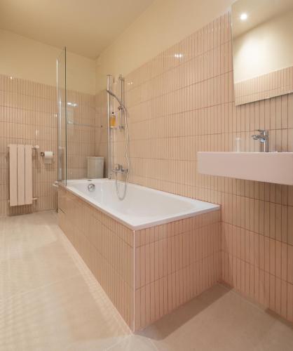 a bathroom with a tub and a shower and a sink at Hotel Louvia in Menton