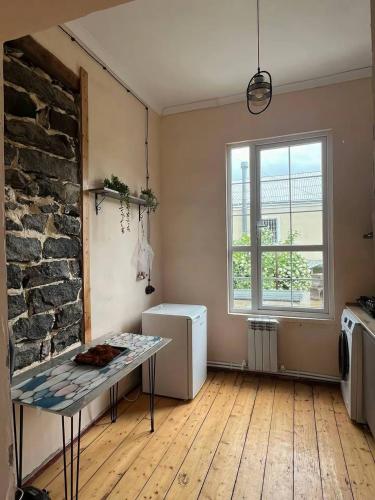 a living room with a table and a stone wall at Green Vibe Guesthouse in Vanadzor