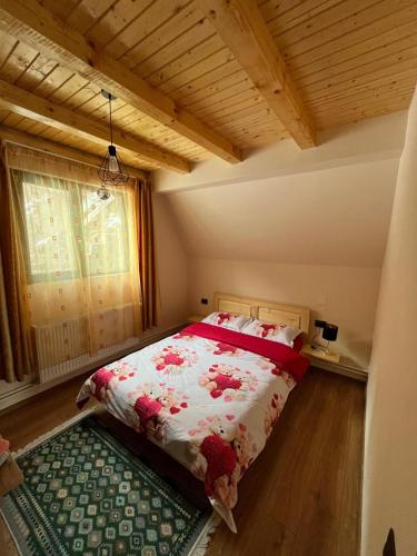 a bedroom with a bed with a red and white blanket at Cabana Doi Brazi A-FRAME in Dămuc