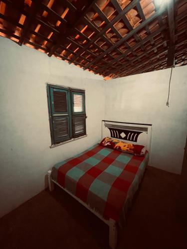 a bedroom with a red and green bed with a window at Casa brisa do mar icapuí in Icapuí