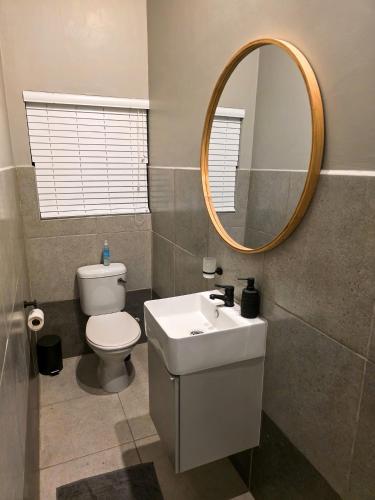 a bathroom with a toilet and a sink and a mirror at West Coast Apartment 85 in Langebaan