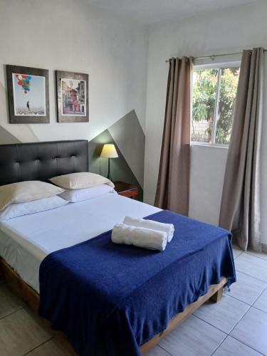ein Schlafzimmer mit einem Bett mit einer blauen Decke und einem Fenster in der Unterkunft Casa Solares in Atlixco