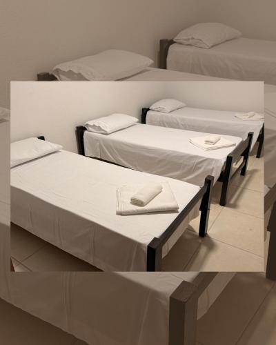 a room with three beds with towels on them at Hostel em Jaguarão in Jaguarão