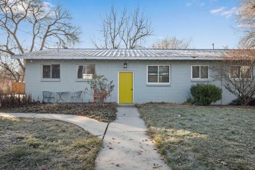 a white house with a yellow door in a yard at Central Bench Garden Guest House in Boise