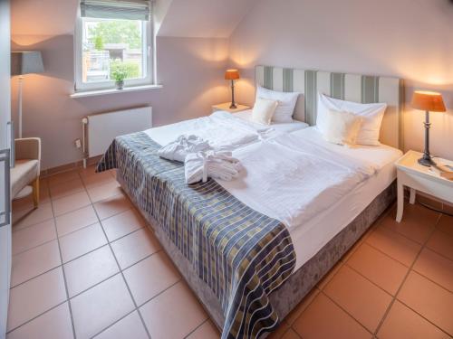 a bedroom with a large bed with white sheets at Hotel Hüttmann in Norddorf