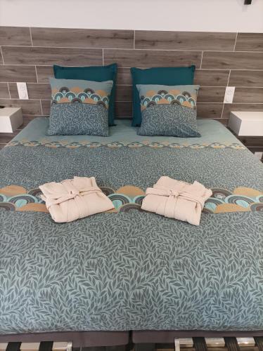 a large bed with two pink pillows on it at L' Har & Lam in Leuilly-sous-Coucy