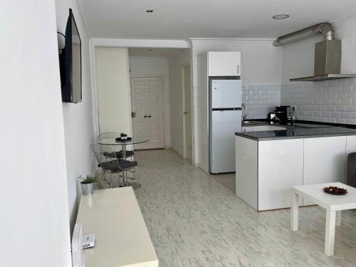 a kitchen with a white refrigerator and a table at Estudio Vista Mar & Piscina - 200 m de la playa in Aguadulce