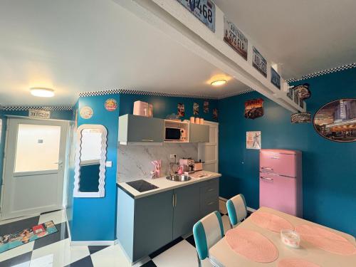 une cuisine aux murs bleus, avec une table et un évier dans l'établissement La suite rétro, 