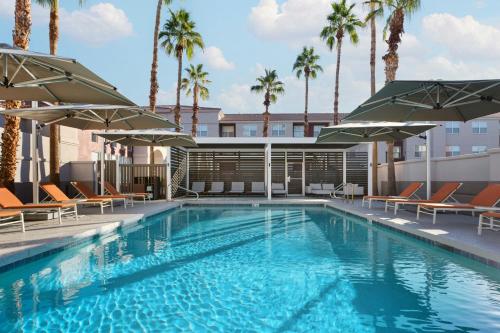 a swimming pool with chairs and umbrellas at Residence Inn Phoenix Mesa in Mesa