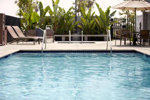 a swimming pool with chairs and an umbrella at Hyatt Place Piedras Negras in Piedras Negras