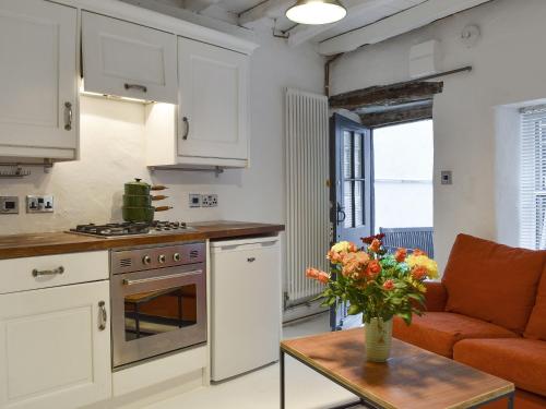a kitchen with white cabinets and a table with a vase of flowers at Hogwood Cottage in Knaresborough