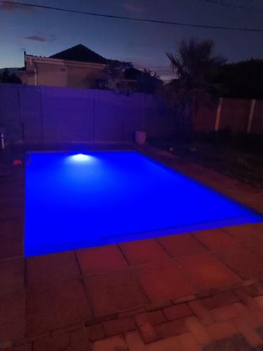 a blue pool in a backyard at night at The Berna in Cape Town