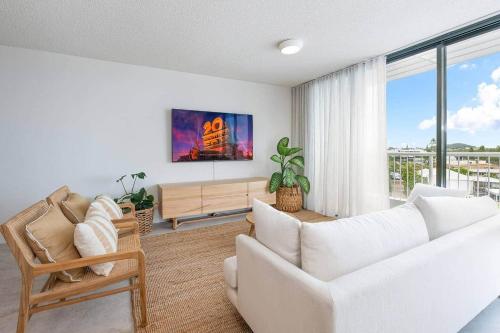 a living room with a white couch and a large window at Coolum Beach Retreat in Coolum Beach