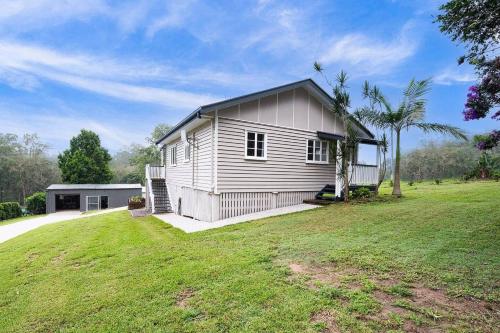 a small white house with a large yard at Glass House Cottage in Glass House Mountains