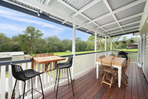 a patio with a table and chairs on a deck at Glass House Cottage in Glass House Mountains