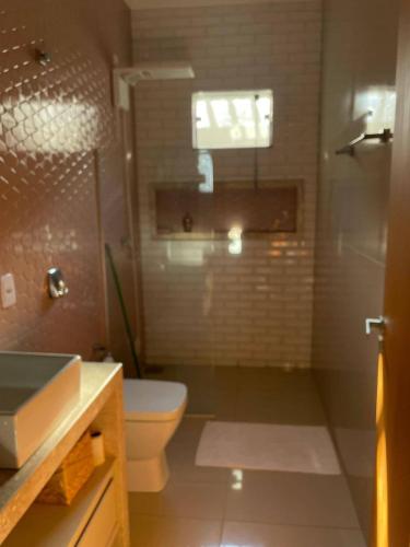 a bathroom with a toilet and a shower and a sink at Pousada e Edícula in Jabuticabal
