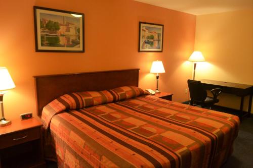 a hotel room with a bed and two lamps at Aurora Park Inn & Suites in Dawson Creek