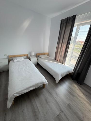 two beds in a white room with a window at Luca House in Remetea Mare