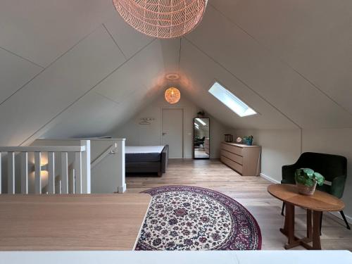 an attic living room with a rug and a table at Erve t Hoolterhof in Holten