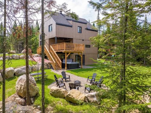 a house with a deck and chairs in the yard at Le Kouzy - Spa, Foosball, Pool table, Game Room in Sainte-Lucie-de-Doncaster
