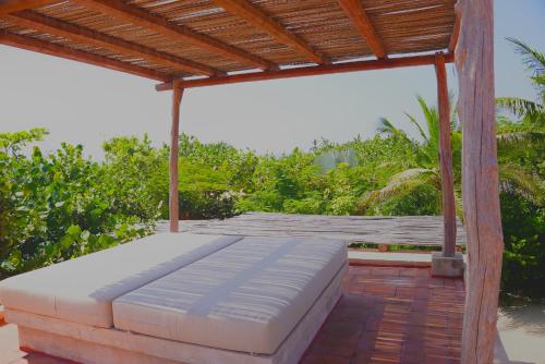 a bed on a patio with a wooden roof at Mazul Puerto Escondido in Tlachicón