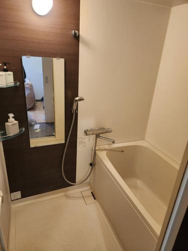a bathroom with a bath tub and a mirror at Mitsubikiya in Matsumoto