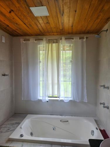 a bath tub in a bathroom with a window at Chalé do Canto - Pé da Serra in Lima Duarte