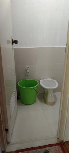 a bathroom with a green bucket next to a toilet at Dapearl Cottage in Baclayon