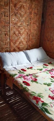 a bed with a floral quilt on top of it at Dapearl Cottage in Baclayon