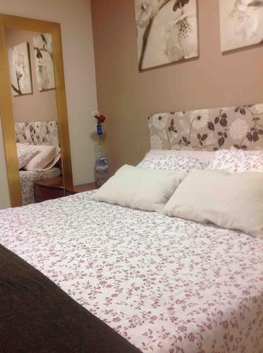 a bedroom with a bed with a floral bedspread at bonito estudio equipado in Alcorcón