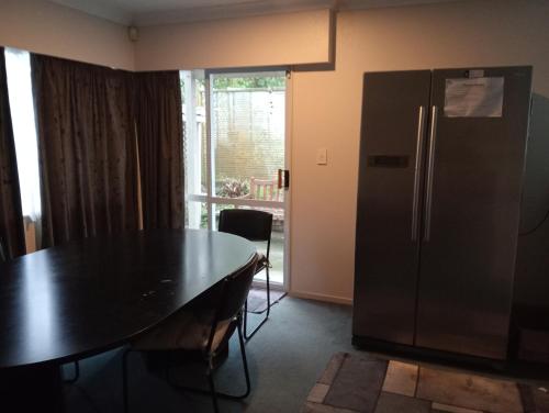 a kitchen with a black table and a refrigerator at Budget shared accommodation holiday room spring city in Tauranga