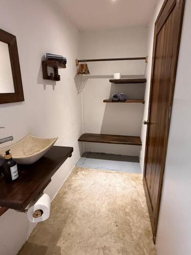 a bathroom with a sink and a wooden door at La baxada mazunte in Mazunte
