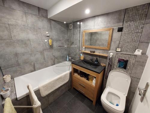 a bathroom with a tub and a toilet and a sink at Chambre privée avec Jardin in Les Ulis