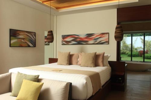 a bedroom with a large white bed and a couch at Kandaya Resort in Daanbantayan
