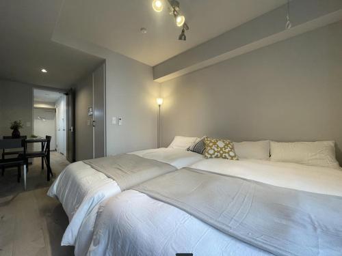 a large white bed in a bedroom with a table at TIC HOTEL Hisayaodorisakae in Nagoya