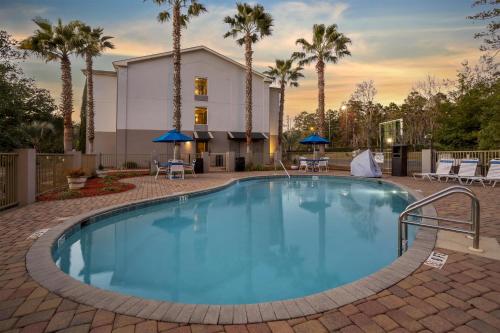 a swimming pool with palm trees and a building at Best Western Plus Tallahassee North Hotel in Tallahassee