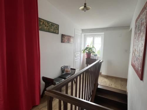 a stairway with a red curtain and a chair at Au pré du puy in Chambretaud