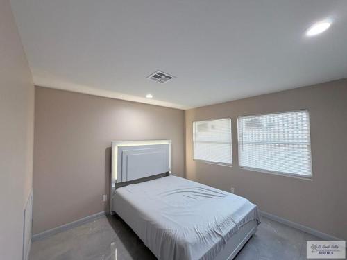 a bedroom with a bed and two windows at 305 Calle Amistosa in Brownsville
