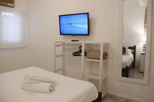 a white room with a tv and a bed and a mirror at Peixe Crew Rua das Pedras in Búzios