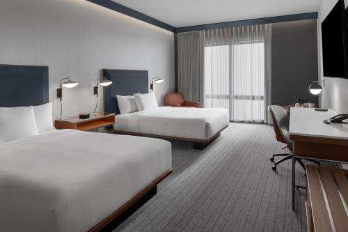a hotel room with two beds and a desk at Courtyard by Marriott Woodland in Woodland