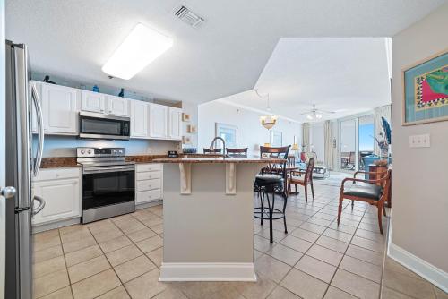 a kitchen and dining room with white cabinets and a table at Palacio Unit 403 in Pensacola