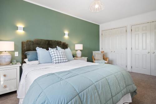 a bedroom with a large bed with blue pillows at Kowhai Apartment-Ground Floor in Pukekohe East