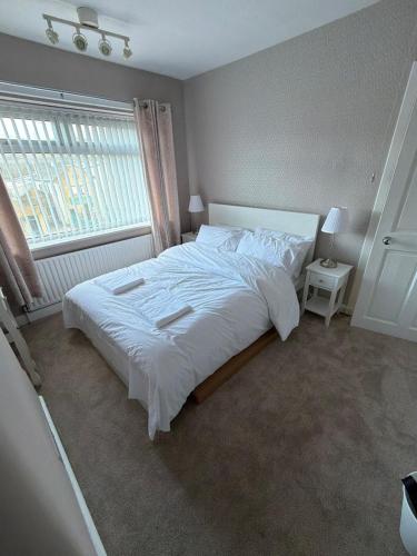 a bedroom with a large white bed and a window at 2 Bed house - Brighouse close to McDonalds and B&M in Brighouse