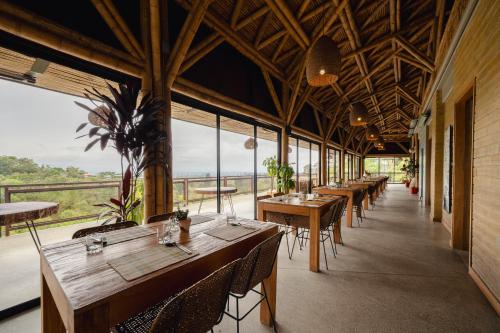 a row of tables and chairs in a room with windows at Cannúa Lodge Hotel in Marinilla